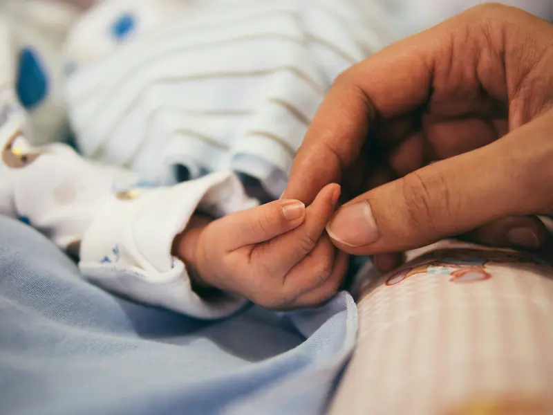 A parent gently holding a child's hand